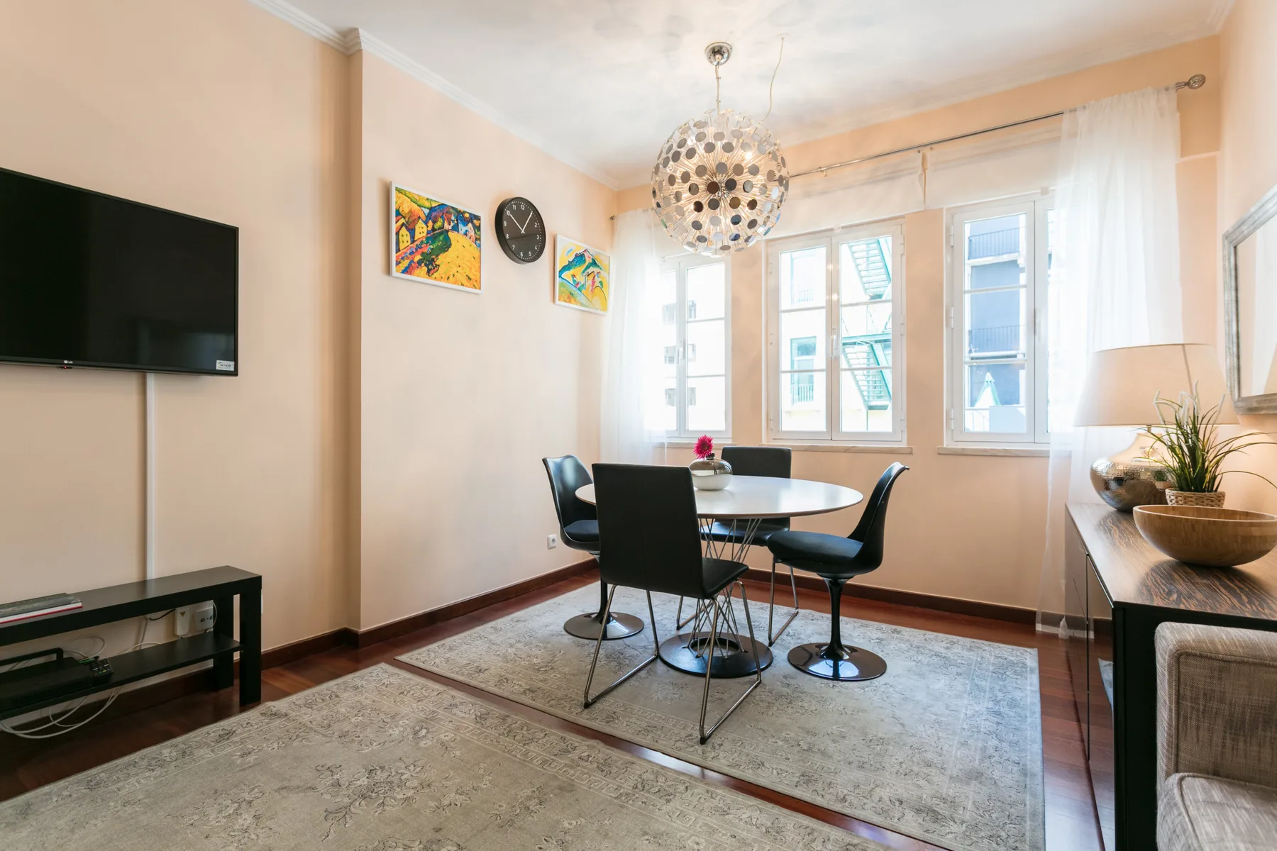 A dining area with a table and chairs beside large windows.