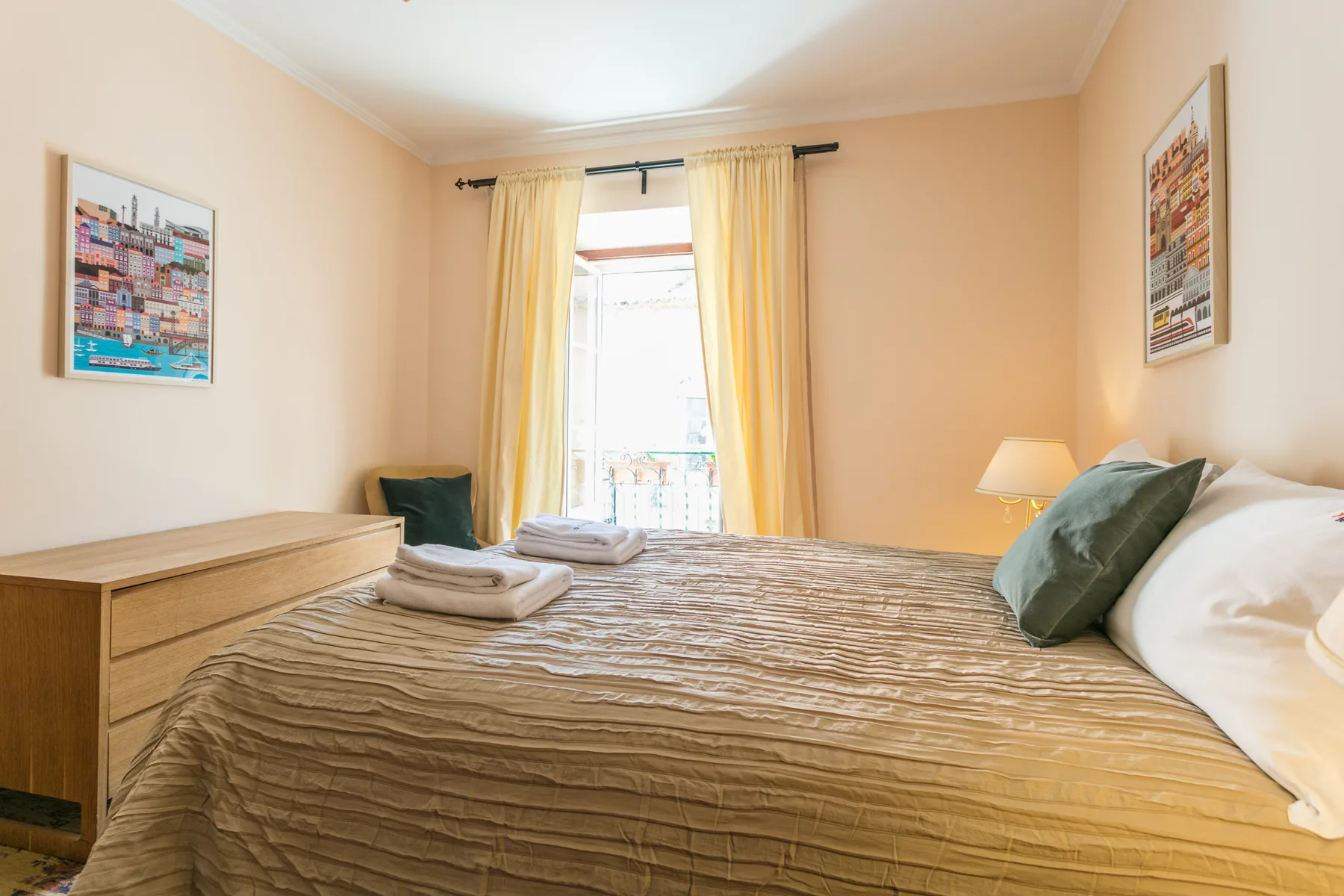 A bedroom with a neatly made bed, bedside lamp, and window with yellow curtains.