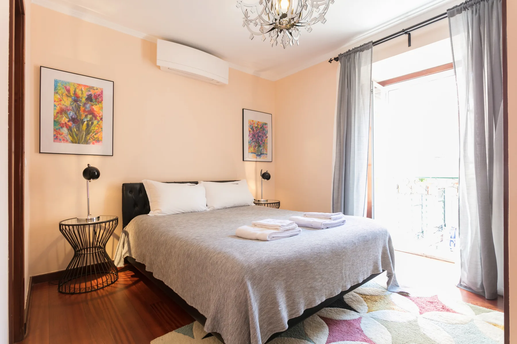 A bedroom with a neatly made bed and large windows.