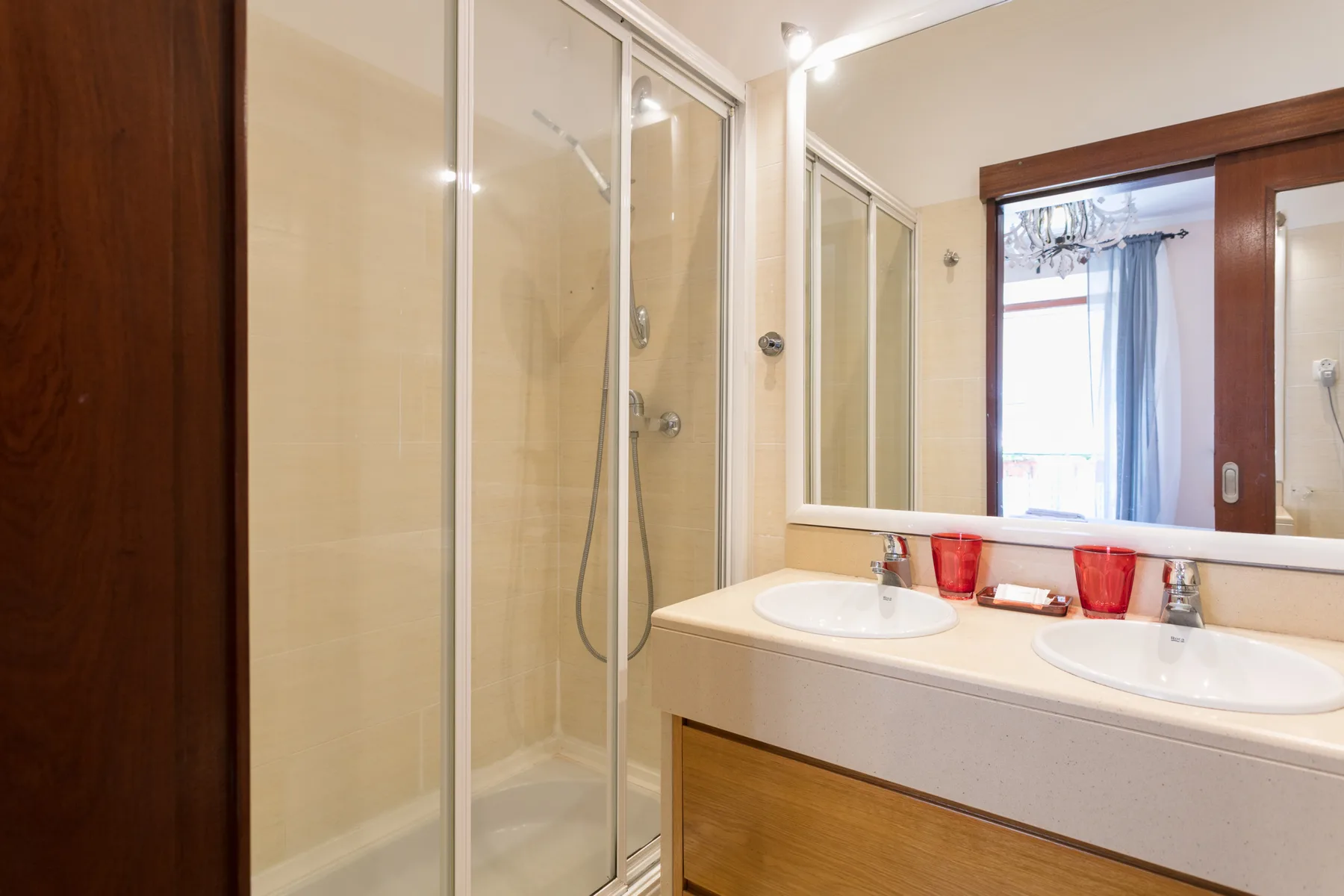A bright bathroom with a glass-enclosed shower and double sink.