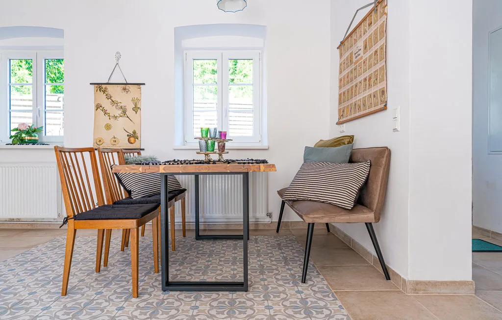 Un comedor luminoso tiene una mesa, asientos de madera y una silla acolchada.