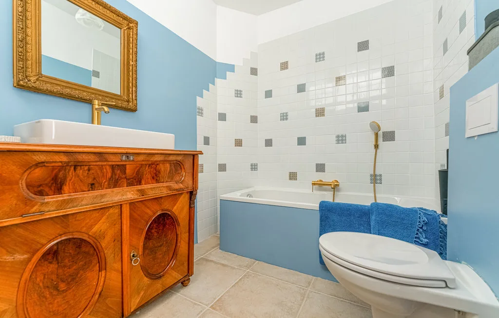 Un baño con bañera, inodoro y mueble de madera.