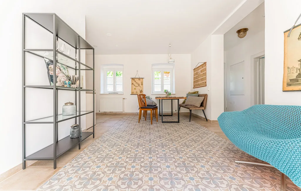 Sala de estar y comedor luminosos con suelo de baldosas estampadas y una mesa.