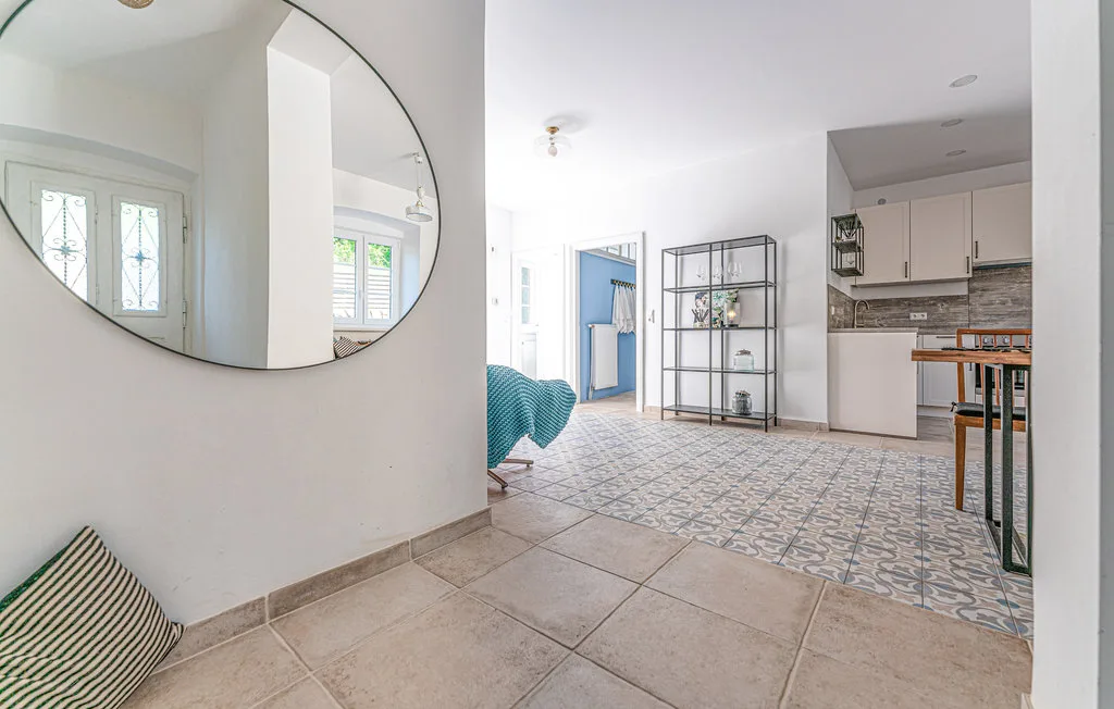 Una habitación luminosa y abierta con cama, estantería y una pequeña cocina.