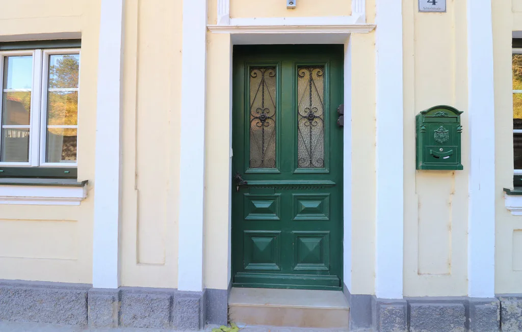 Una puerta de entrada verde en la fachada de un edificio claro.