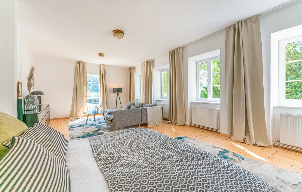 Una sala luminosa con asientos, ventanas grandes y cortinas largas.