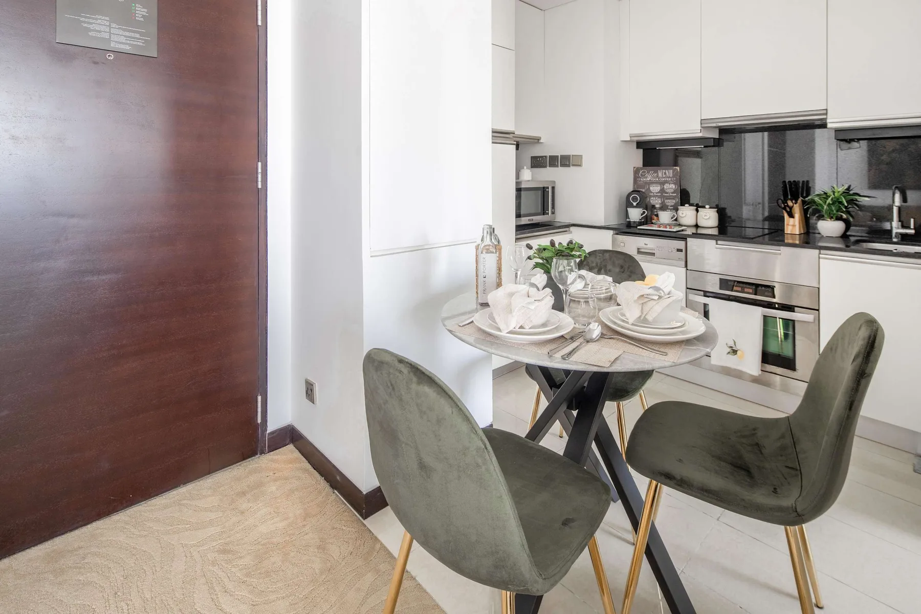 Un comedor con la mesa puesta está junto a una cocina moderna.