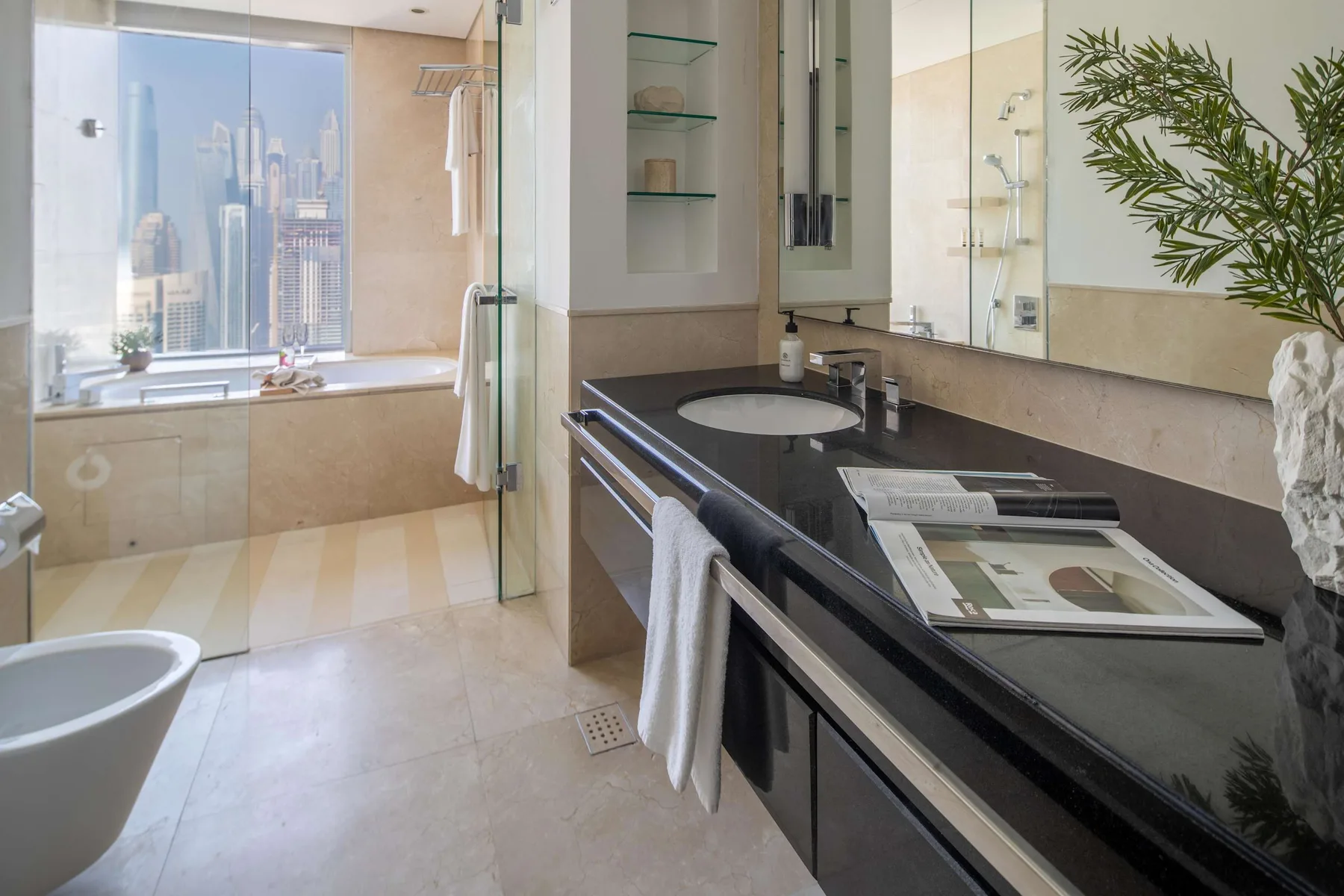 Un baño con un mueble oscuro, una bañera y una ventana grande con vista a la ciudad.