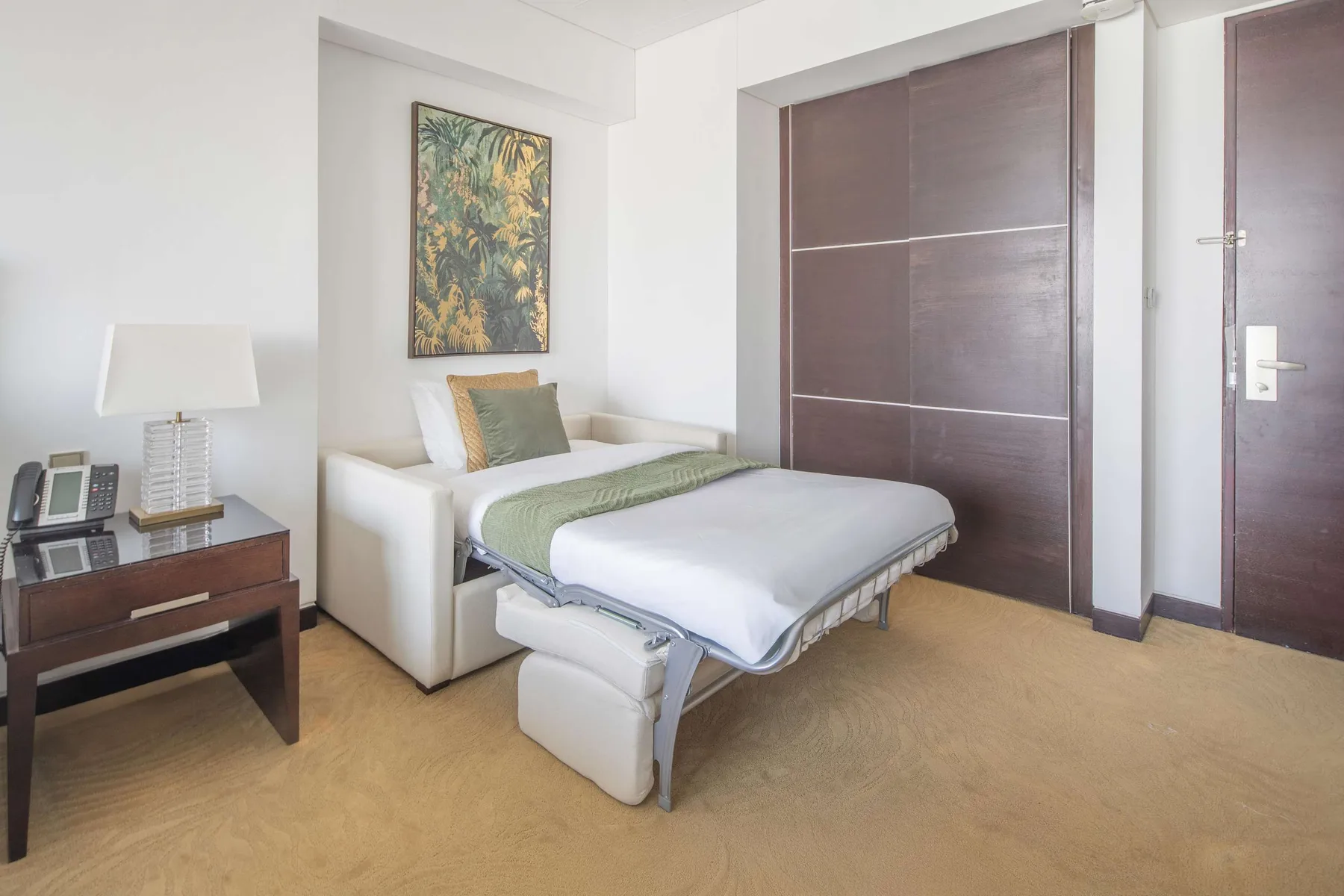 Un dormitorio con una cama, una mesita y un cuadro en la pared.