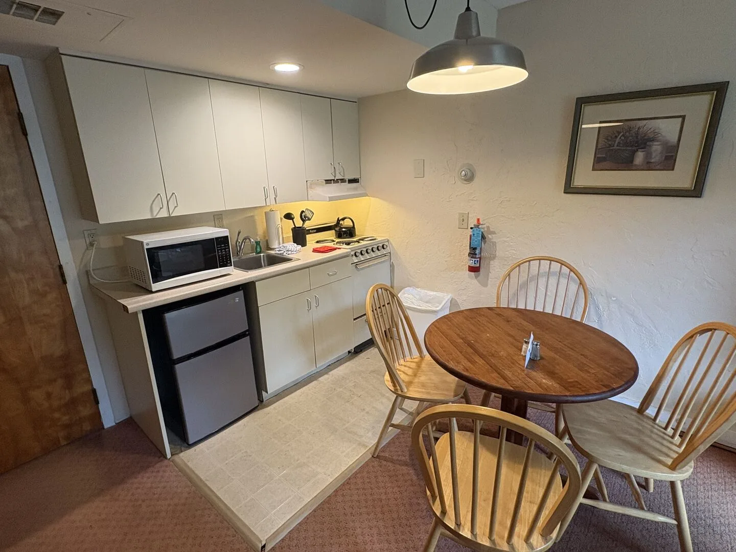 Una cocina compacta y zona de comedor con una mesa redonda de madera y sillas.