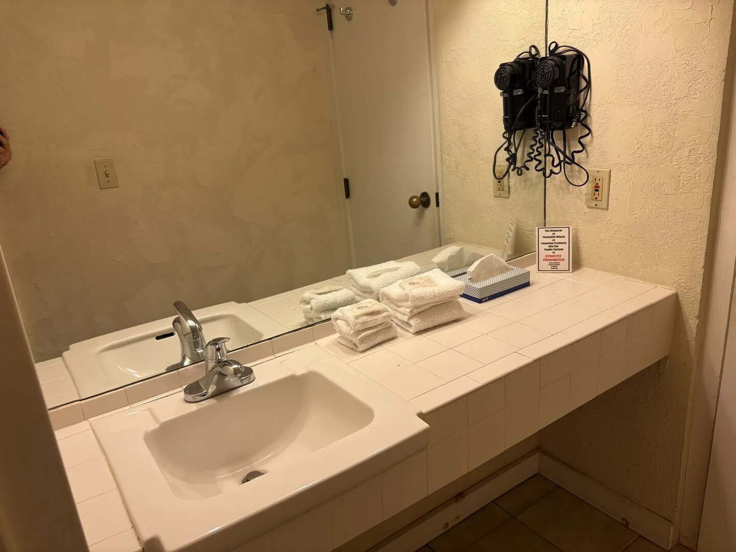 Un tocador de baño con lavabo, espejo y toallas dobladas.