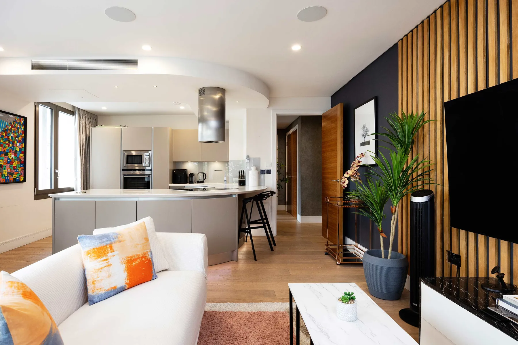 An open-plan living room and kitchen with a white seating area and kitchen island.