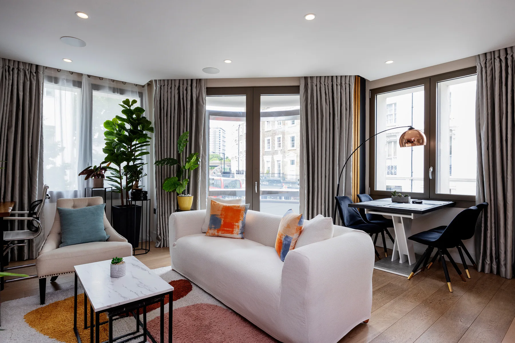 A bright living room with seating, a coffee table, and large windows.