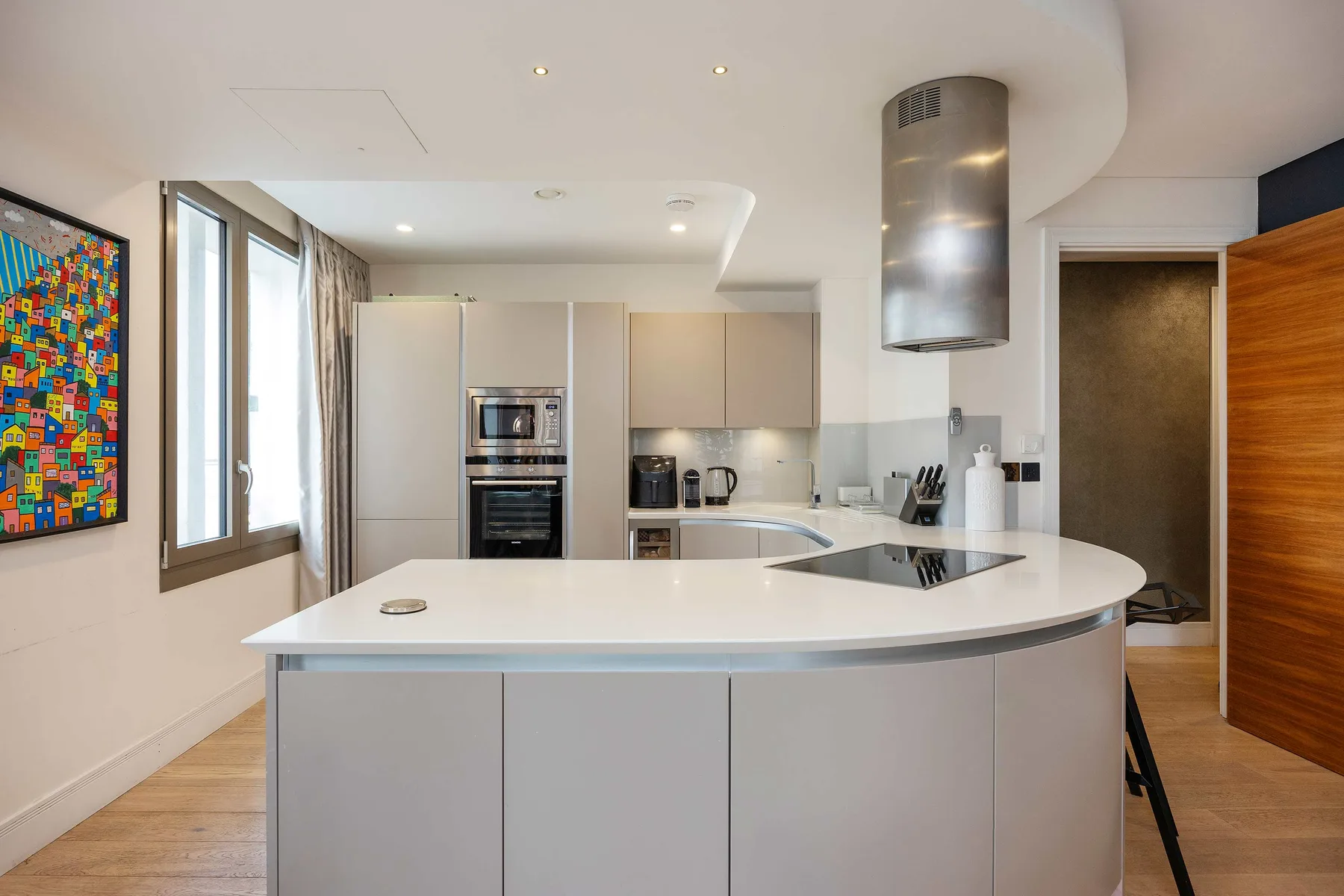A modern kitchen with a curved island and built-in appliances.