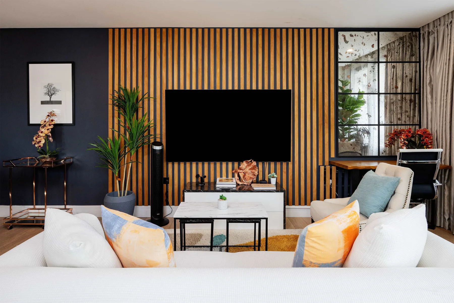 A living room with seating facing a television on a striped accent wall.