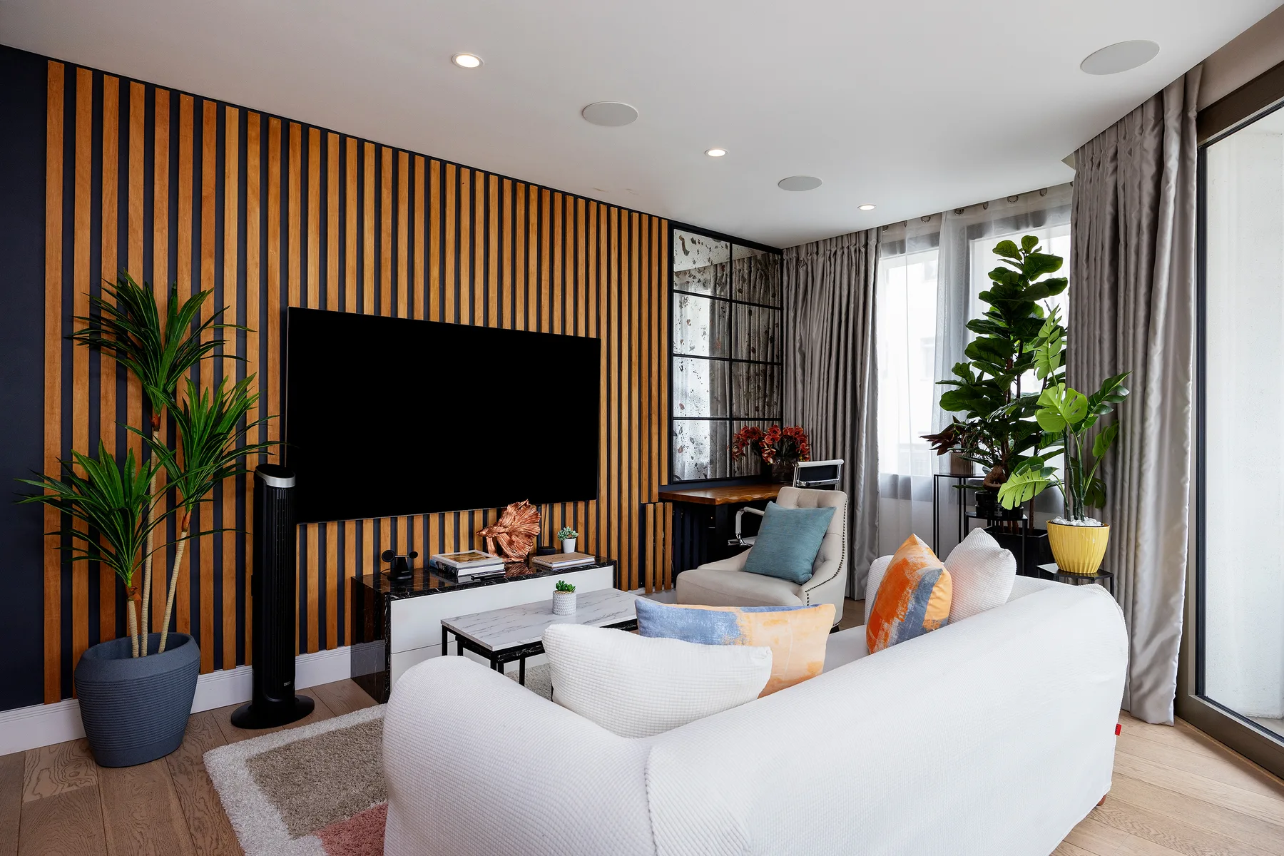 A bright living room with a television wall and seating around a coffee table.