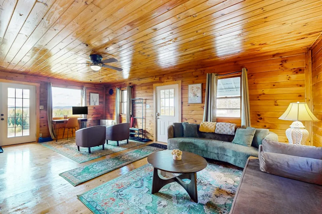 A wood-paneled living room with sofas, a coffee table, and a ceiling fan.