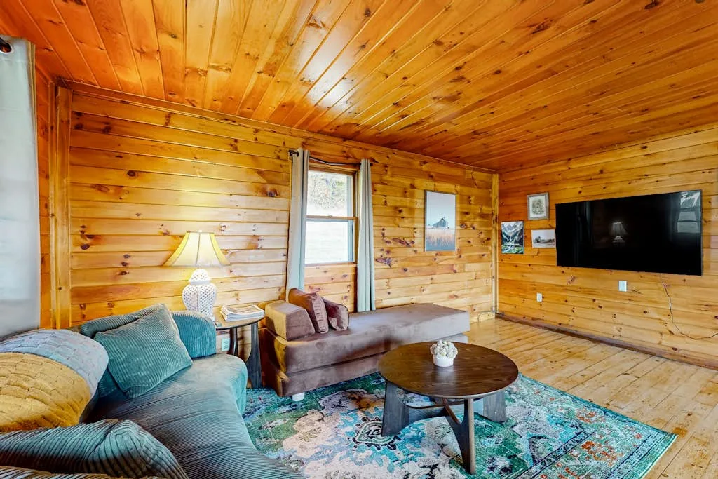 A wood-paneled living room with seating, a coffee table, and a wall-mounted television.