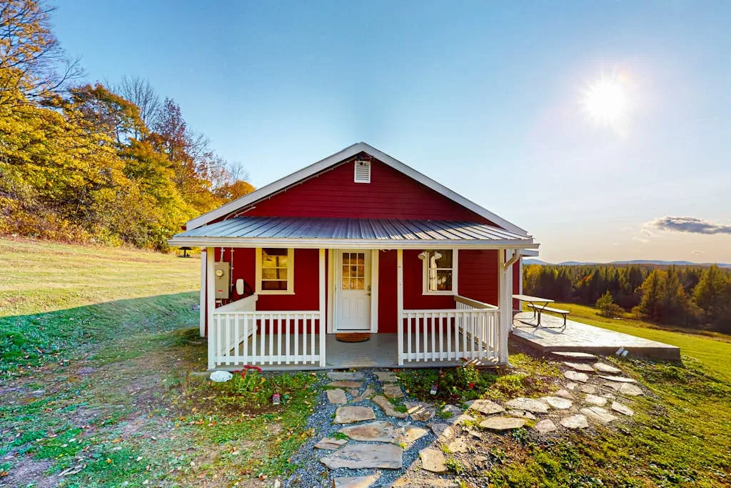 A red cottage with a white front porch sits beside a stone path.