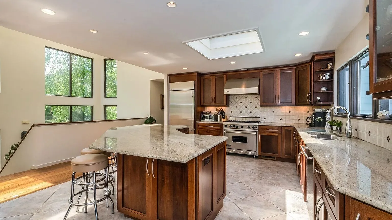Una cocina amplia con gabinetes oscuros, una isla central y ventanas grandes.