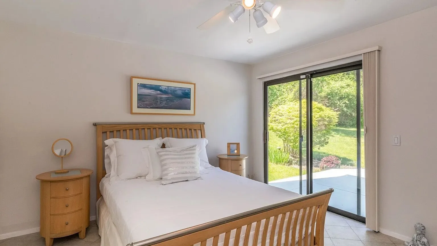 Un dormitorio con una cama y puertas corredizas de vidrio que dan a un jardín.