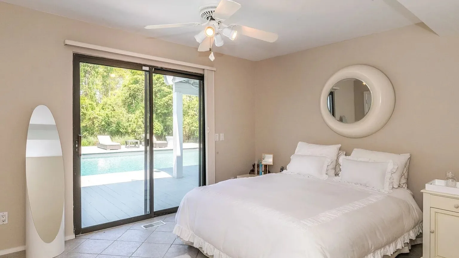 Un dormitorio luminoso con una cama bien arreglada y puertas corredizas de vidrio.