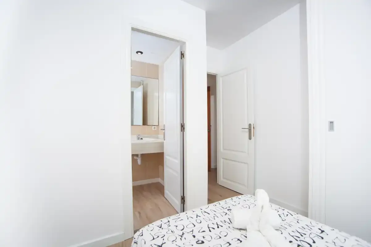 Un dormitorio con ropa de cama estampada y una puerta abierta hacia un baño.