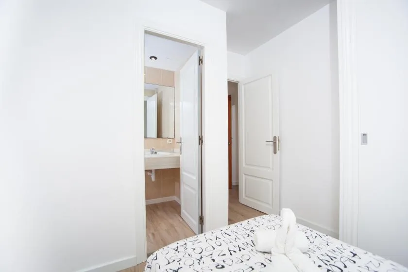 Un dormitorio con una colcha estampada y una puerta abierta hacia un baño.