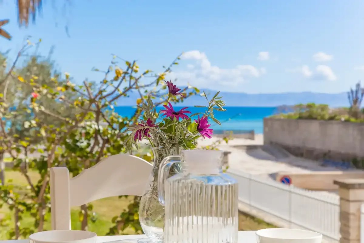 Una terraza junto al mar con un jarrón de flores y vistas al agua.