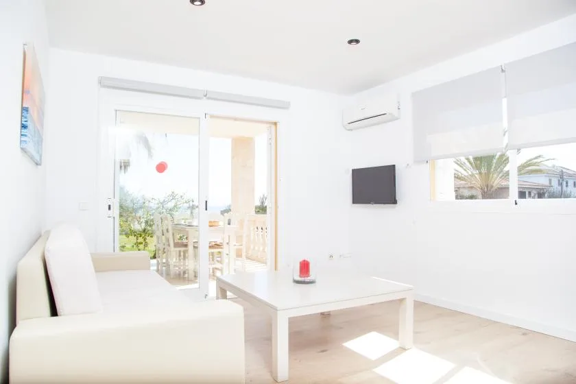 Una sala luminosa con asientos y una mesa baja junto a puertas de vidrio.