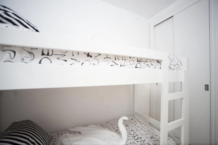 Un dormitorio con una litera blanca y ropa de cama estampada.