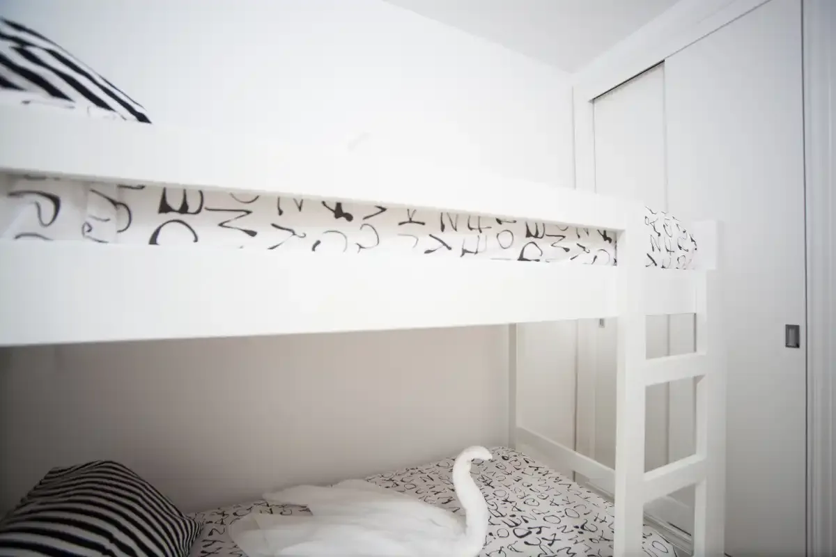 Un dormitorio con una litera blanca y ropa de cama estampada.