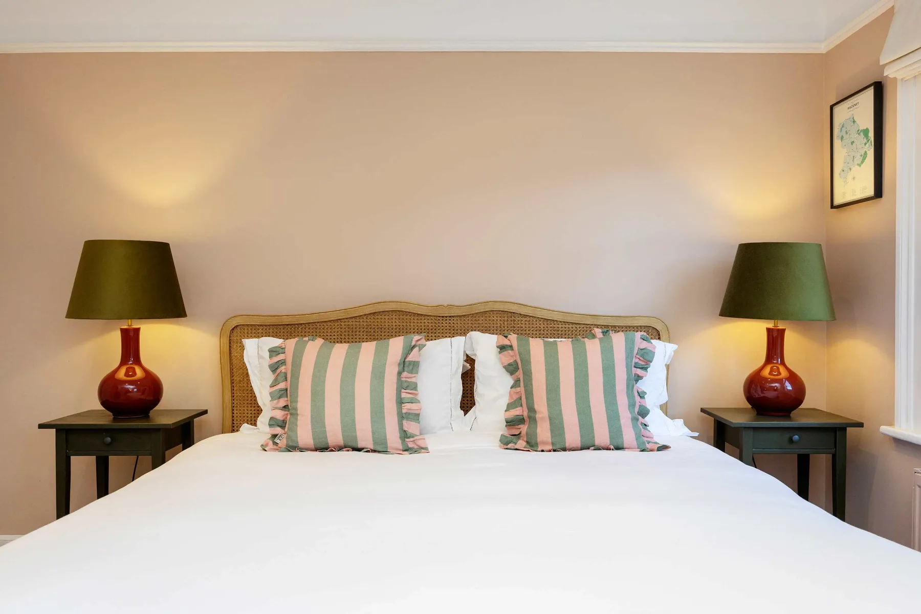 A bedroom with a neatly made bed and matching bedside lamps.