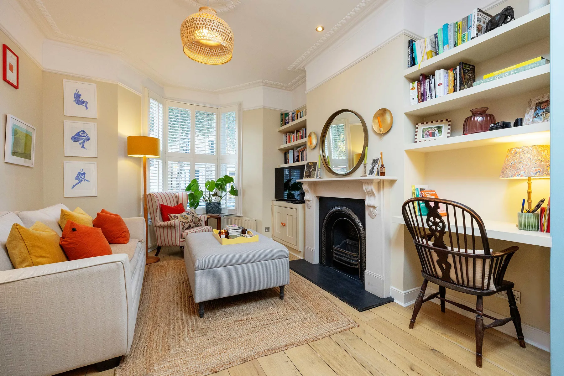A bright living room with a fireplace, seating, and built-in bookshelves.