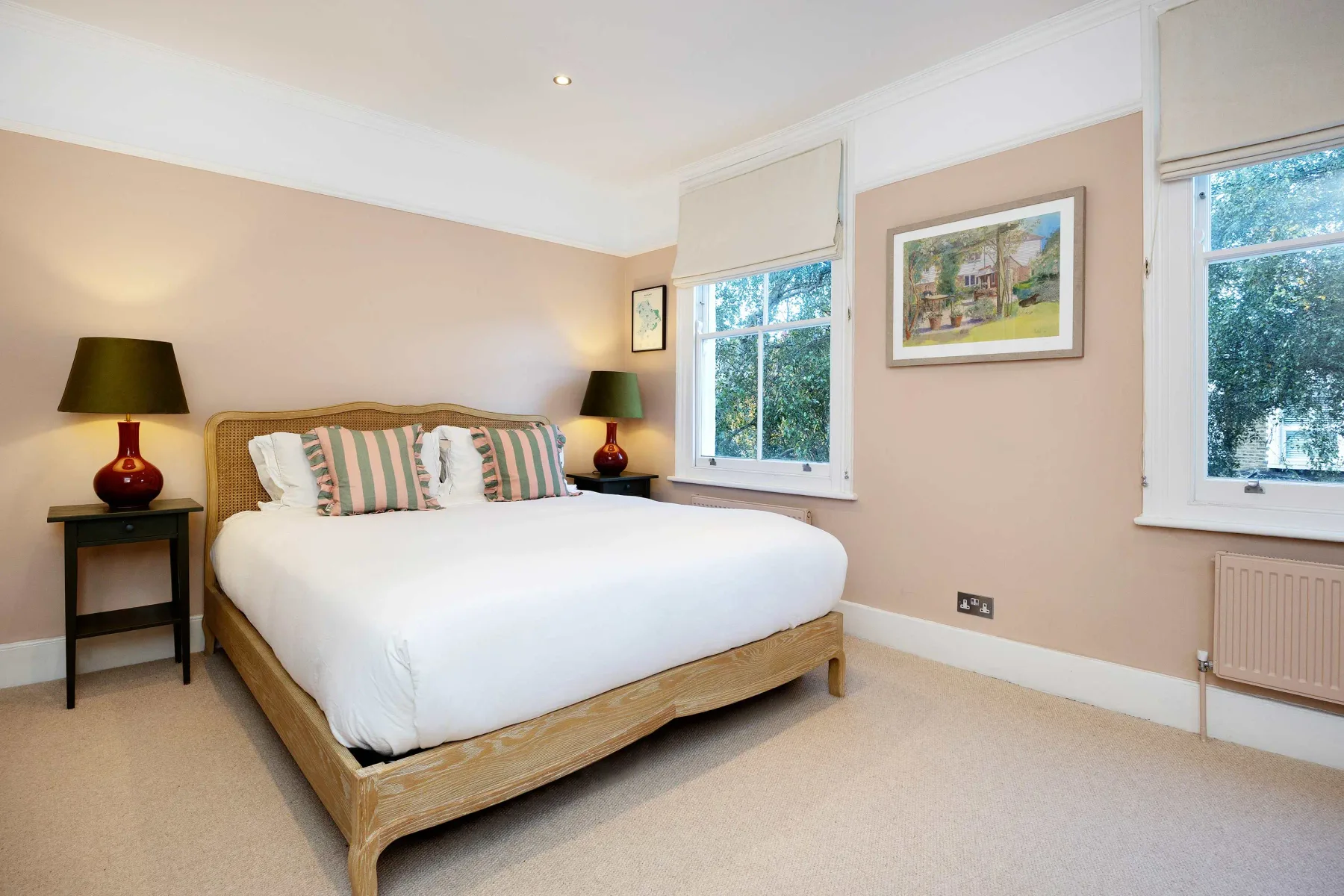 A bedroom with a bed, bedside tables, and windows.