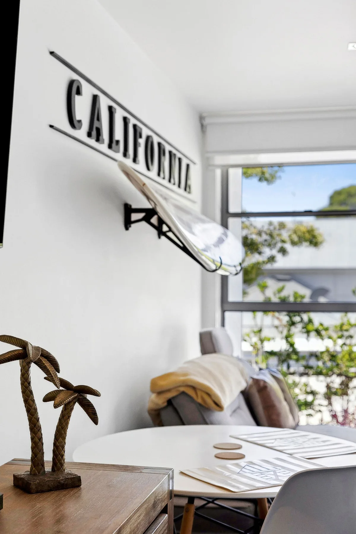 A bright room with a California sign, seating, and a large window.