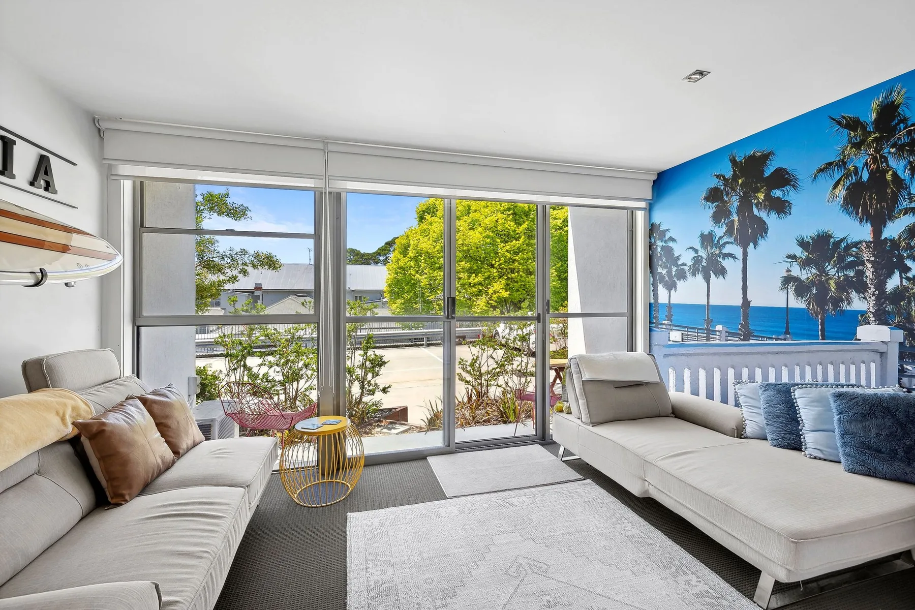 A bright living room with seating beside large windows and a view of the ocean.