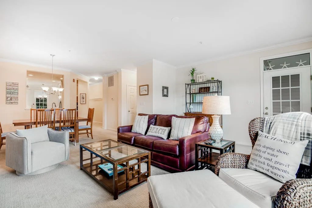 A living room with seating, a coffee table, and a dining area in the background.