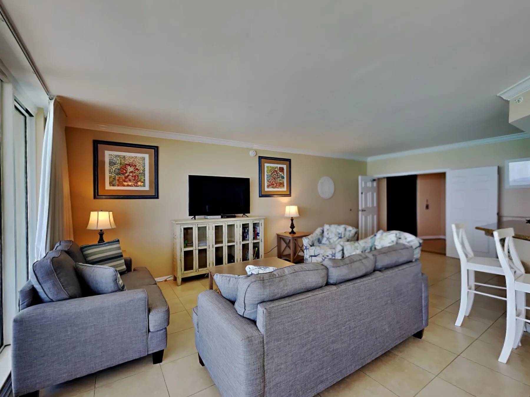 A living room with gray seating, a television, and a dining table.
