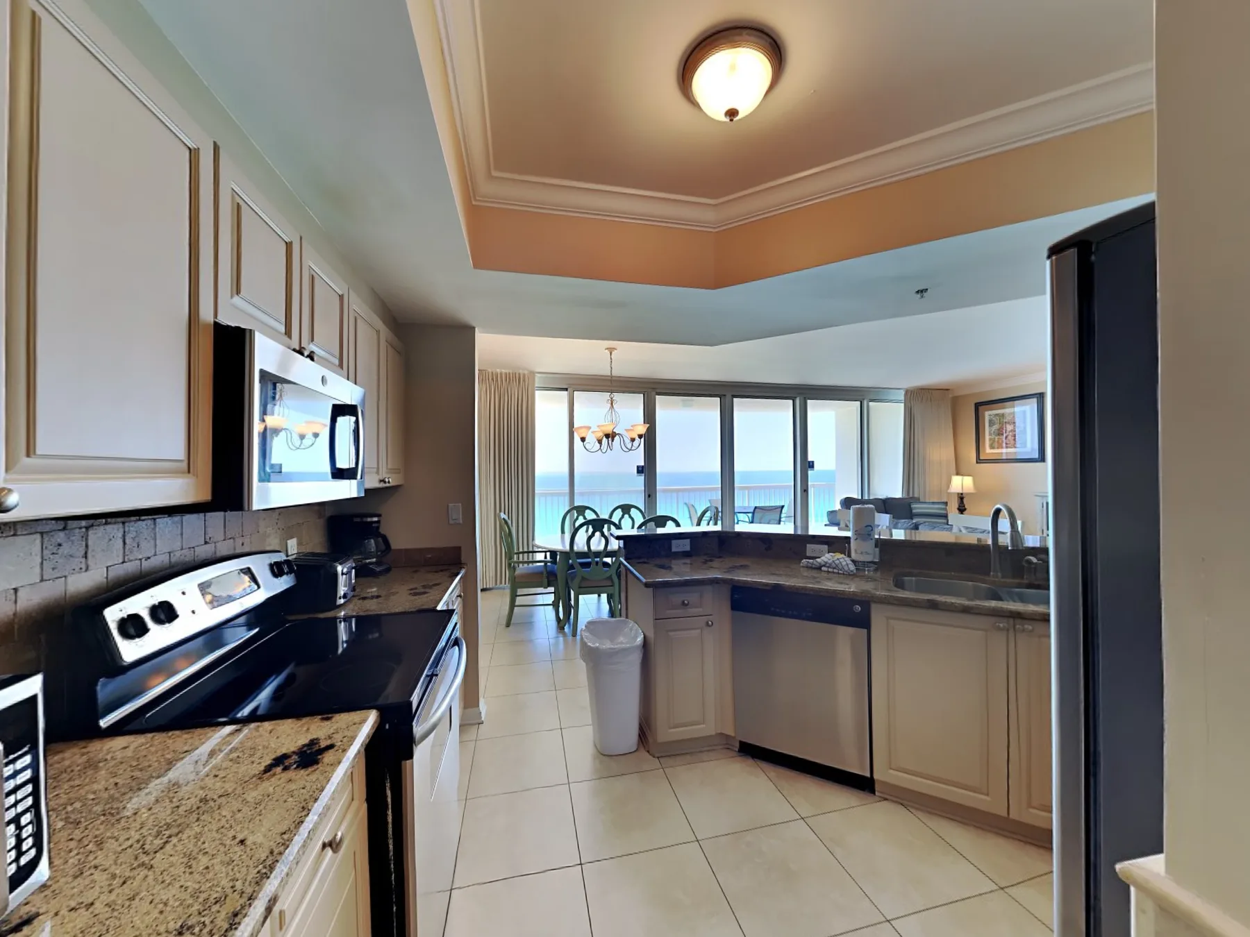 A kitchen with dark countertops opens onto a dining area with ocean views.
