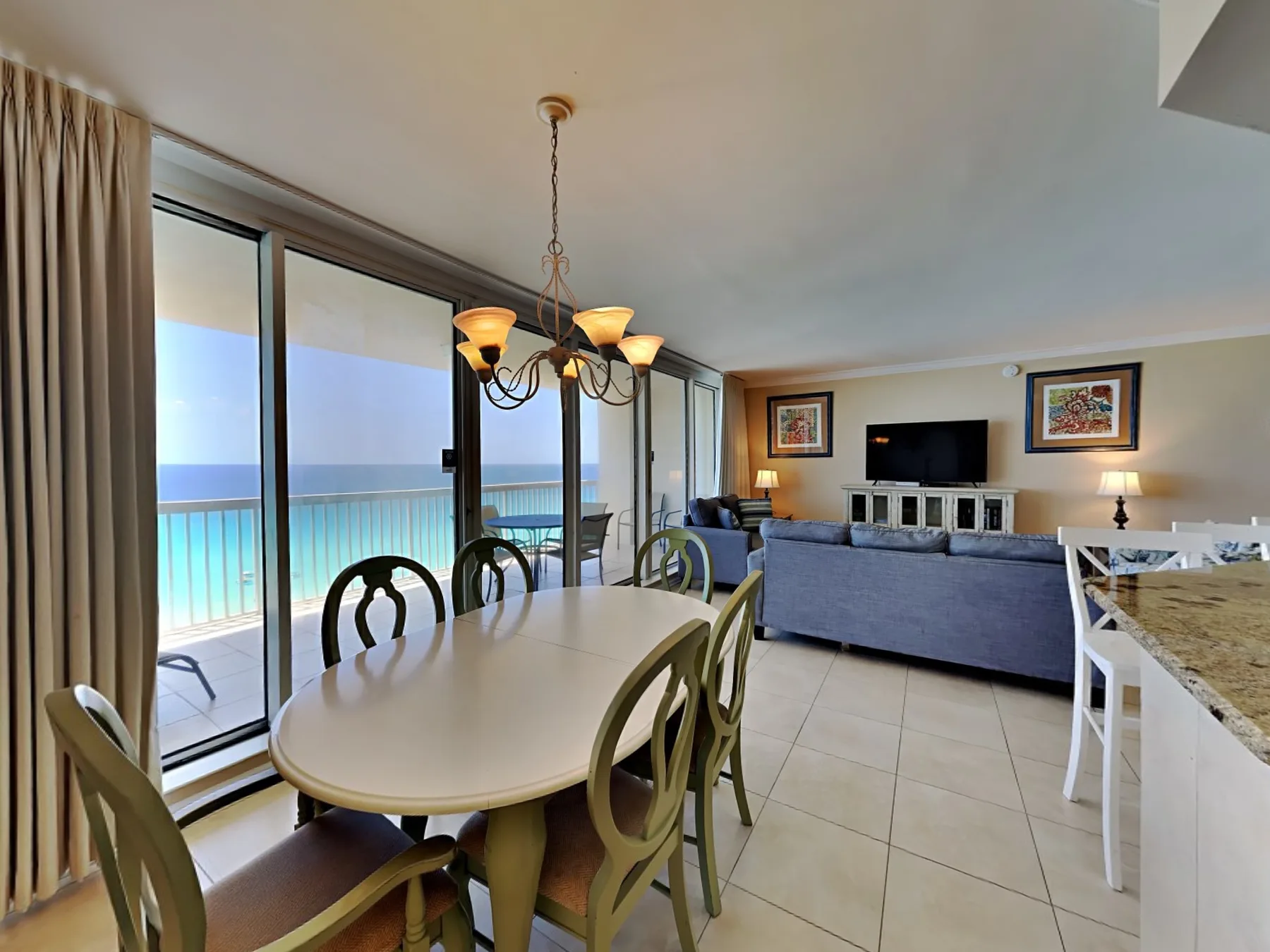 An open living and dining area has a table beside sliding glass doors overlooking the water.