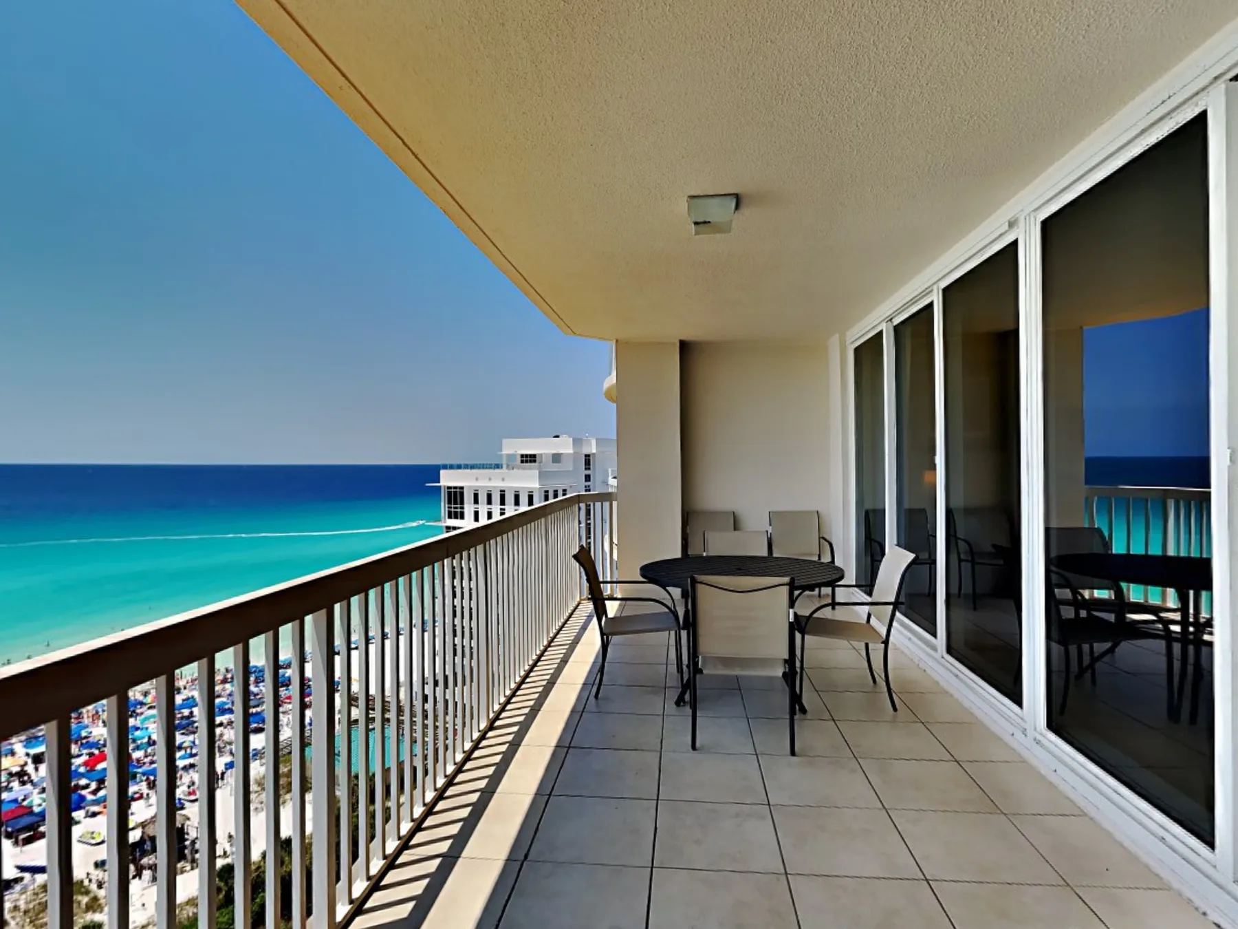 A balcony with seating overlooks the beach and turquoise ocean.