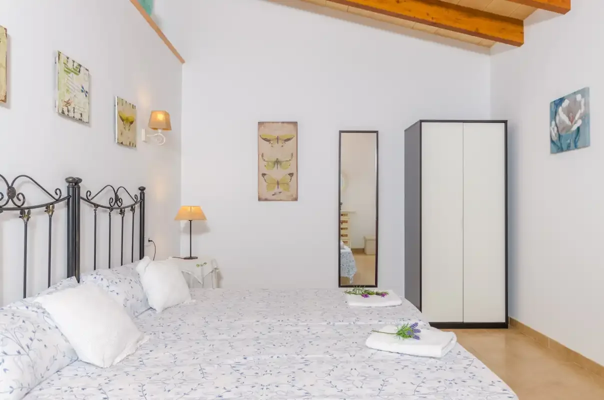 A bedroom with a double bed, patterned bedding, and a wardrobe.