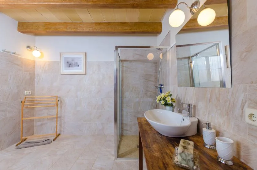 A tiled bathroom has a glass shower and a sink on a wooden vanity.