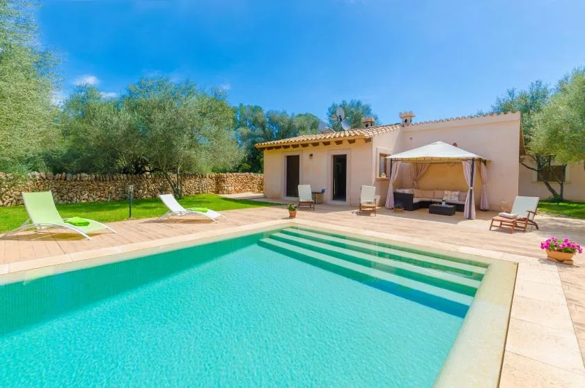 An outdoor swimming pool beside a patio and a single-story house.