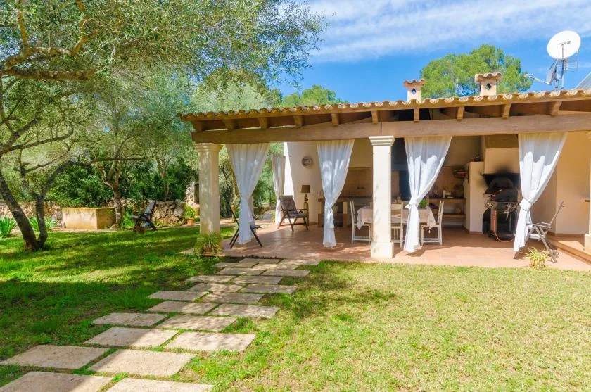A covered outdoor patio opens onto a grassy garden, with seating beneath the roof.