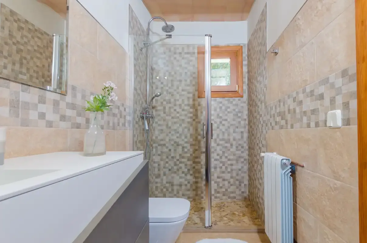 A tiled bathroom with a shower, sink, and small window.