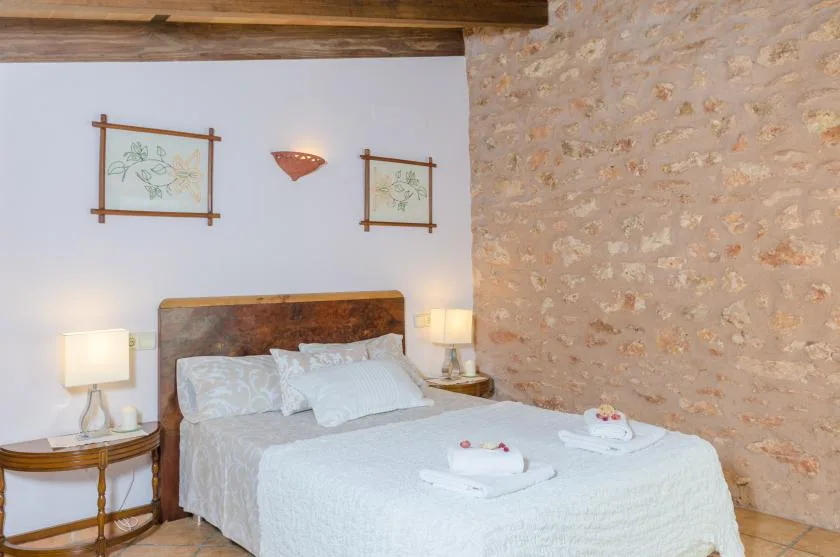 A bedroom with a double bed, bedside tables, and framed wall art.