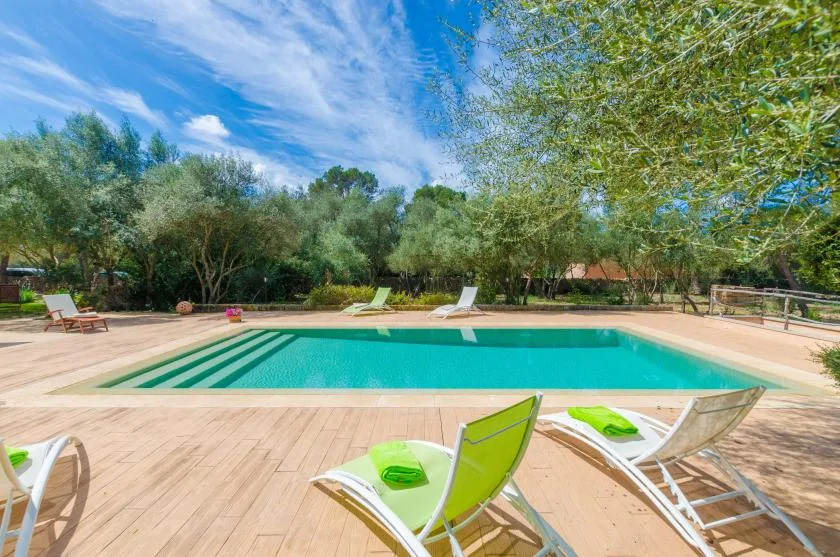 An outdoor swimming pool is surrounded by a wooden deck and lounge seating.