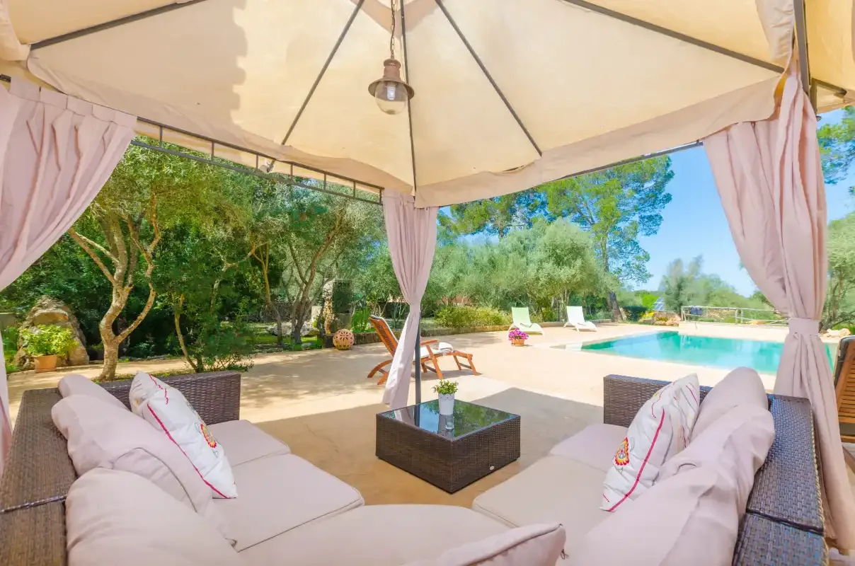 A shaded outdoor seating area overlooks a swimming pool and landscaped garden.